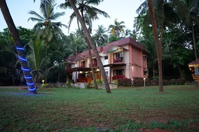 a pink house with palm trees in front of it at Club 7 Beach Resort in Kannur