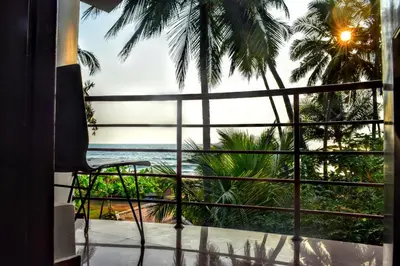 a room with a view of the ocean from a balcony at Club 7 Beach Resort in Kannur