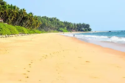 a beach with footprints in the sand and the ocean at Club 7 Beach Resort in Kannur