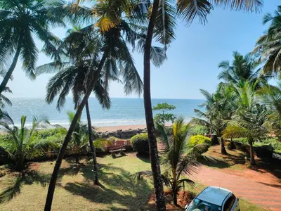a car parked next to a beach with palm trees at Club 7 Beach Resort in Kannur
