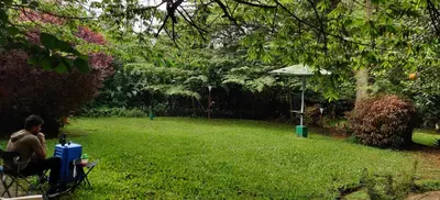 a man sitting in a chair in a yard at Mysticgreens Home Stay in Piriyāpatna