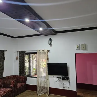 a living room with a couch and a flat screen tv at Mysticgreens Home Stay in Piriyāpatna