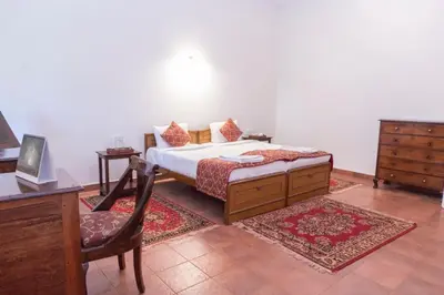 a bedroom with a bed and a desk and a chair at Villa Fair Winds, Sirukundra Estate in Vālpārai