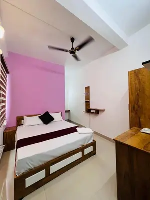 a bedroom with a bed with a pink wall at SN RESiDENCY in Kozhikode