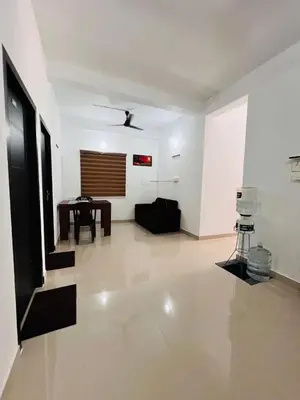 a living room with a table and a white wall at SN RESiDENCY in Kozhikode