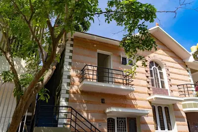 a house with a balcony and a tree at Akshaya - Charming 2BHK apartment with scenic view in Mysore