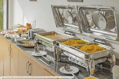 a kitchen counter with several trays of food at Treebo Sadhoo Heritage in Kannur