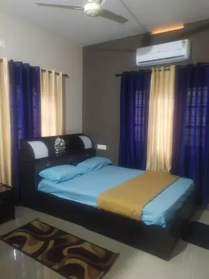 two beds in a bedroom with blue curtains at Mayoorvihar home stay Sulthaan Bathery Wayanad Kerala in Sultan Bathery
