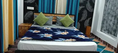 a bed with a blue comforter and green pillows at Royal Valley Apartment in Kalpetta