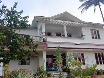 a white house with a balcony at Royal Valley Apartment in Kalpetta