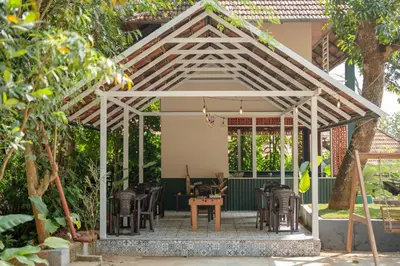 a gazebo with chairs and tables in a garden at Swastha Royal Resort Wayanad in Kaniyāmbetta