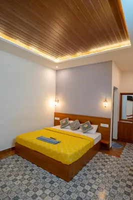 a bedroom with a bed with a yellow comforter at Swastha Royal Resort Wayanad in Kaniyāmbetta