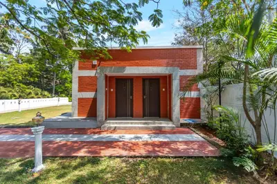 a red brick building with a black door at Mango Hill Coimbatore-Near Isha Yoga in Alāndurai