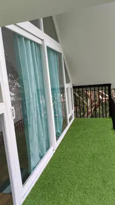 a balcony with green grass and large windows at Nomadcasa Rooms in Kanthalloor