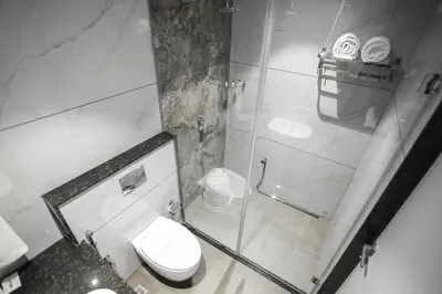 a bathroom with a toilet and a glass shower at Hotel Lakshmi Towers in Kāngayam