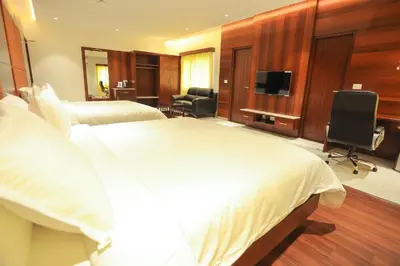 a hotel room with two beds and a flat screen tv at Hotel Lakshmi Towers in Kāngayam