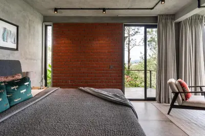 a bedroom with a brick wall and a bed at LohonoStays Amani Villa 11B in Coonoor