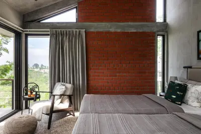 a bedroom with a brick wall and a bed and a chair at LohonoStays Amani Villa 11B in Coonoor