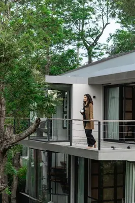 a woman standing on a balcony talking on a cell phone at LohonoStays Amani Villa 11B in Coonoor