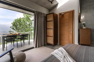 a bedroom with a bed and a balcony with a table at LohonoStays Amani Villa 12A in Coonoor