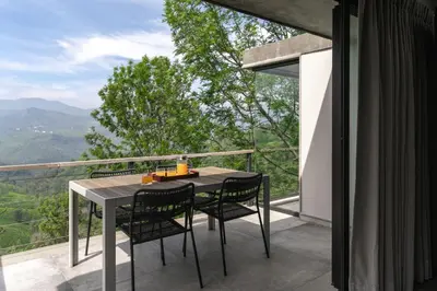 a table and chairs on a balcony with a view at LohonoStays Amani Villa 12A in Coonoor