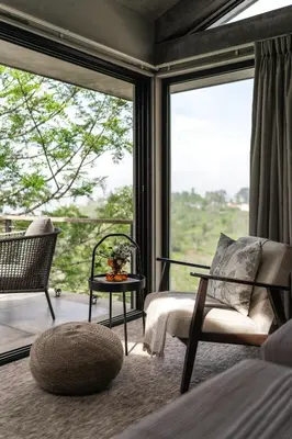 a bedroom with a large window with a chair and a table at LohonoStays Amani Villa 12A in Coonoor