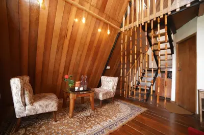 a hallway with two chairs and a table and stairs at Eagle Woods Kookal in Kūkkāl