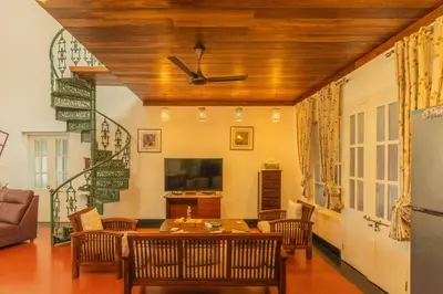 a living room with a table and chairs and a ceiling at Bougainville, Wayanad in Kalpetta