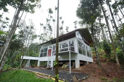 a white house in the middle of a forest at Areca Valley Farmstay in Agali