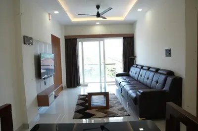 a living room with a leather couch and a tv at Theeram Residency in Iringal