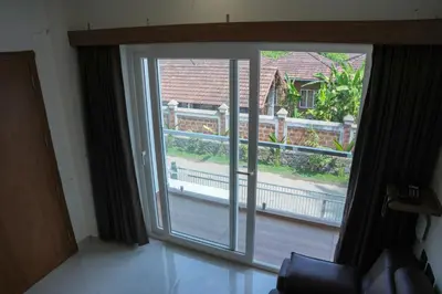 a large sliding glass door with a view of a house at Theeram Residency in Iringal