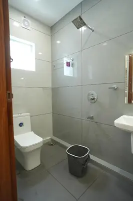 a bathroom with a shower and a toilet and a sink at Theeram Residency in Iringal
