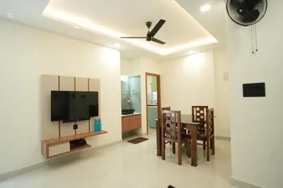 a living room with a television and a table and chairs at Theeram Residency in Iringal