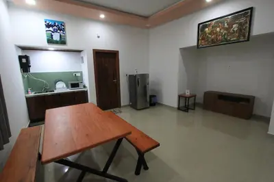 a room with a wooden table and a kitchen at Wayanad One in Wayanad