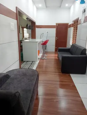 a living room with a couch and a kitchen at Izzath in Kottakkal