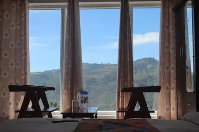 a bedroom with a large window with a view of a mountain at THE DEW stay Three bedroom villa in Kodaikānāl