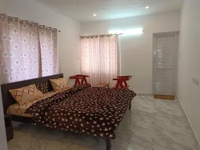 a bedroom with a bed and two chairs in it at THE DEW stay Three bedroom villa in Kodaikānāl
