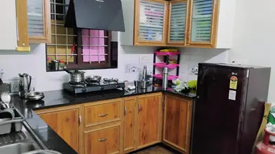 a kitchen with a black refrigerator and wooden cabinets at Cozy Corner in Alwaye