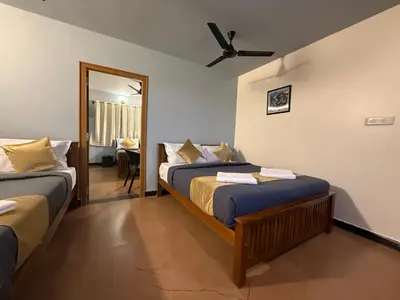 a bedroom with two beds and a mirror at Humming Bird suite in Kotagiri
