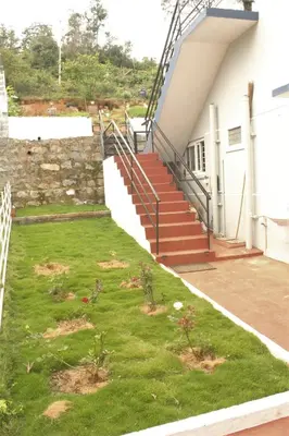 a grassy yard with stairs on the side of a building at Casa by the hills in Kotagiri