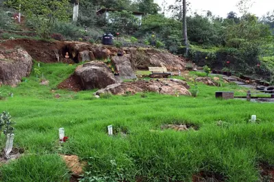 a garden with green grass and rocks and a bench at Casa by the hills in Kotagiri