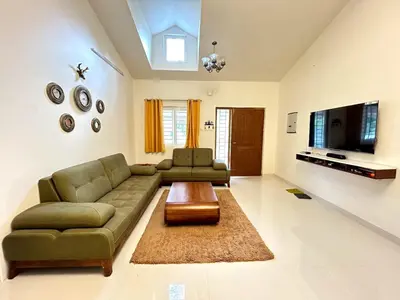a living room with a couch and a tv at Casa by the hills in Kotagiri