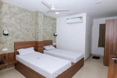 a bedroom with two beds and a ceiling fan at Balu Residency - A Business Class Hotel in Coimbatore