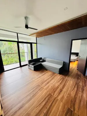 a living room with a couch and wooden floors at AYD-IN BY GREENLEAVES Resort in Vythiri