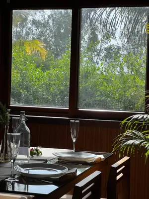 a table with glasses and plates on it with a window at Jungle flare in Hampāpura