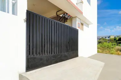 a black gate on the side of a white house at Super Hotel O Neelambur Near PSG ITech in Coimbatore