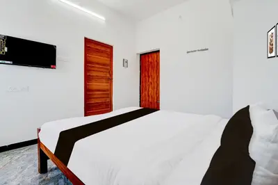 a bedroom with a bed and a tv on the wall at Super Hotel O Neelambur Near PSG ITech in Coimbatore