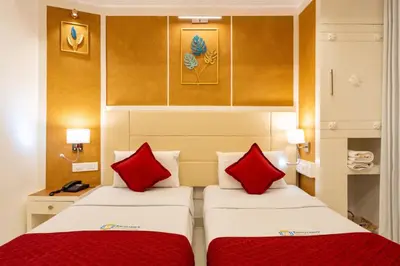 two beds in a hotel room with red pillows at Excellency Airport Hotel in Angamali