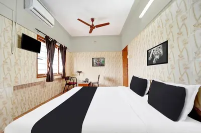 a bedroom with a large white bed with a ceiling fan at Super Hotel O Tiruppur Near Railway station in Tiruppūr