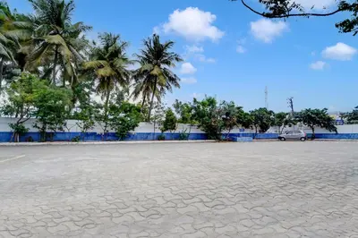an empty parking lot with palm trees in the background at Super Hotel O Tiruppur Near Railway station in Tiruppūr